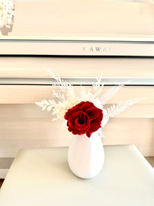 Small preserved red rose in a white slim vase